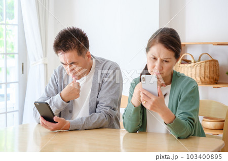 困った表情でスマートフォンを使うシニア夫婦 困った表情でスマートフォンを使うシニア夫婦 103400895