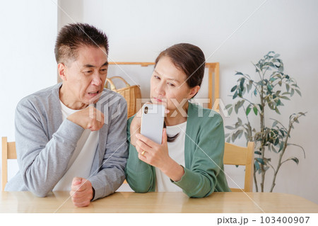 困った表情でスマートフォンを使うシニア夫婦 困った表情でスマートフォンを使うシニア夫婦 103400907
