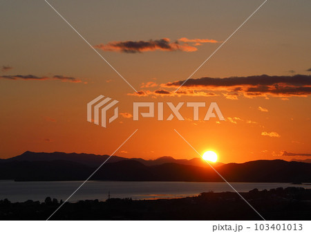 猪苗代湖対岸の山並みに大きな太陽が白く輝き、オレンジ色に染まる空が印象的で綺麗だ。 103401013