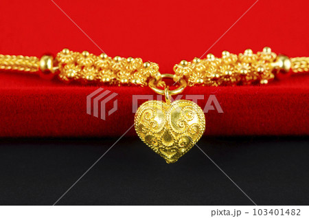 The Gold necklace and heart shape pendant and gold ring on red velvet box. The Gold necklace and heart shape pendant and gold ring on red velvet box. 103401482