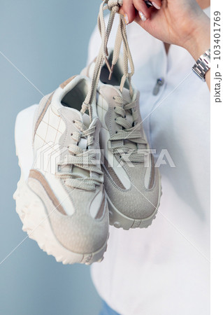 a woman's hand holds a pair of comfortable shoes in her hands. sneakers. woman is ready for walk. High quality photo 103401769