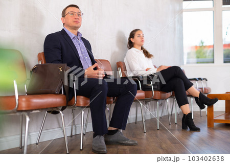 Middle-aged male visitor sitting on the bench in waiting room of clinic 103402638