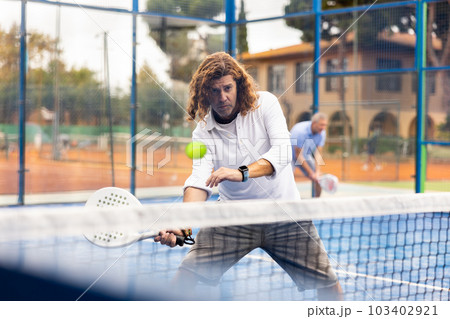 Sporty resolved man playing padel on open court 103402921