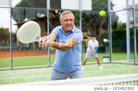 Emotional mature man playing paddle tennis outdoors 103402992