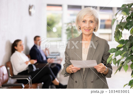 Glad old woman standing with her back to waiting room 103403001