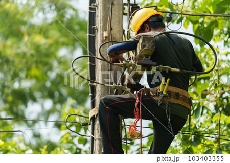 technician climbing electric poles and connecting wires 103403355