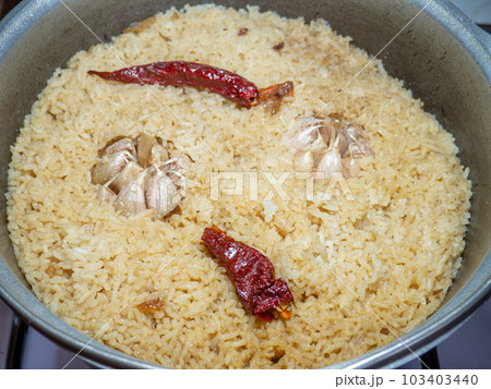 Ready Uzbek pilaf in a cauldron. Red hot pepperb head of garlic. Boiled piss. Asian cuisine dish. Ready Uzbek pilaf in a cauldron. Red hot pepperb head of garlic. Boiled piss. Asian cuisine dish. 103403440