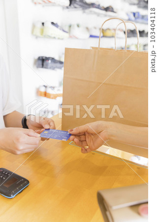靴屋さんで靴を買ってクレジットカードで支払いをする若い女性手元 靴屋さんで靴を買ってクレジットカードで支払いをする若い女性手元 103404118