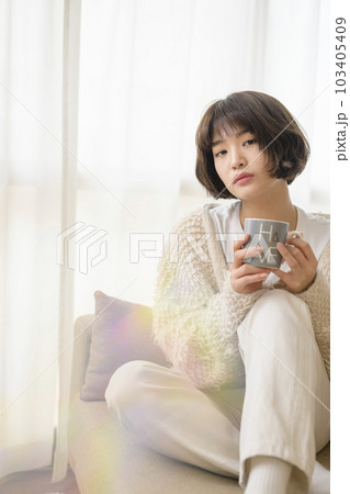 ソファでくつろぐ若い女性（フィルター使用） 103405409