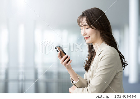 オフィスでスーツ姿でスマホを見たりかけようとする女性 103406464