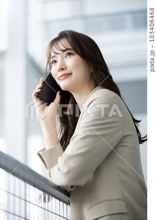 オフィスでスーツ姿でスマホ持って通話する笑顔の美人な女性 縦 オフィスでスーツ姿でスマホ持って通話する笑顔の美人な女性 縦 103406468
