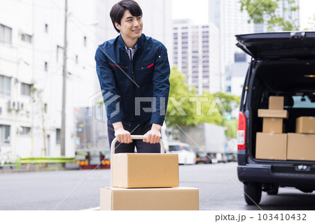 物流　台車で荷物を運ぶ配達員 103410432