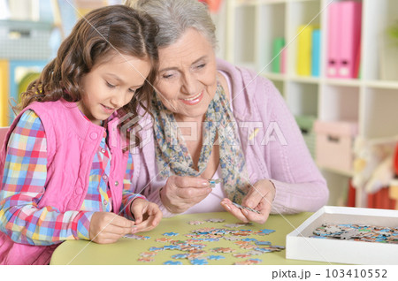 Grandmother with little granddaughter collecting puzzle Grandmother with little granddaughter collecting puzzle 103410552