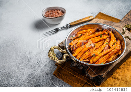 Roasted sweet potato french fries in a skillet with herbs. White background. Top view. Copy space Roasted sweet potato french fries in a skillet with herbs. White background. Top view. Copy space 103412633