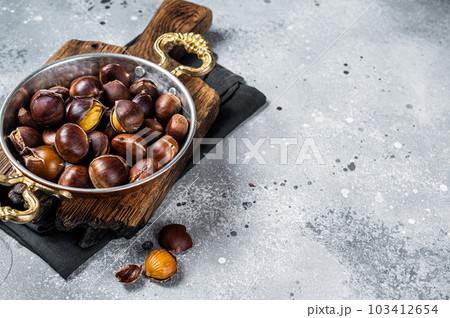 Cracked roasted chestnuts served in a skillet. Gray background. Top view. Copy space Cracked roasted chestnuts served in a skillet. Gray background. Top view. Copy space 103412654
