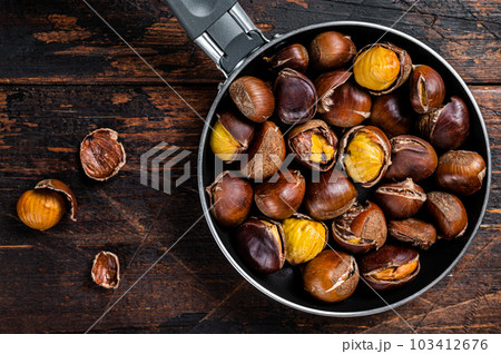 Roasted chestnuts nuts in a pan. Wooden background. Top view Roasted chestnuts nuts in a pan. Wooden background. Top view 103412676