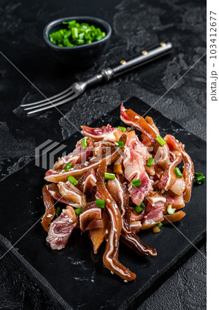 Fried pig ears with sesame seeds and green onions. Fried pork ears in korean style with spicy sauce. Black background. Top view 103412677