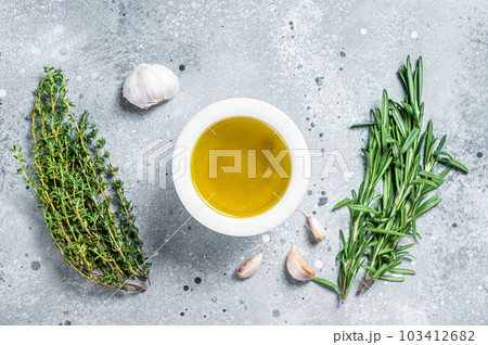 Olive oil with fresh herbs on kitchen table. Top view. Copy space Olive oil with fresh herbs on kitchen table. Top view. Copy space 103412682