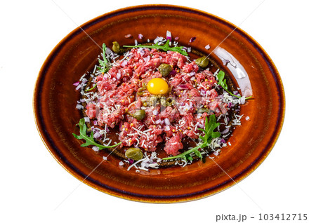 Beef steak tartare with raw egg yolk, pickled capers and Parmesan cheese. Isolated on white background. Beef steak tartare with raw egg yolk, pickled capers and Parmesan cheese. Isolated on white background. 103412715