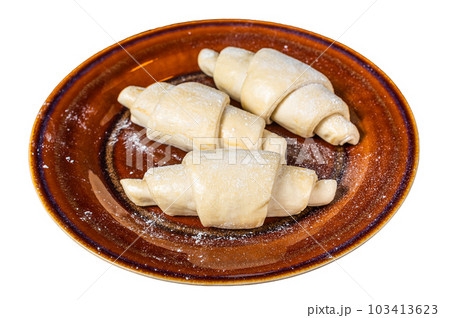 Raw uncooked homemade croissant on a rustic plate. Isolated on white background. 103413623