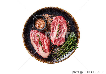 Chuck eye Roll beef steaks, raw meat on a plate with thyme and herbs. Isolated on white background. Chuck eye Roll beef steaks, raw meat on a plate with thyme and herbs. Isolated on white background. 103413892
