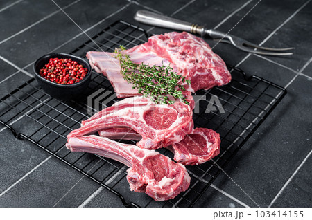Fresh Raw lamb meat chop steaks on kitchen table with spices and herbs. Black background. Top view 103414155
