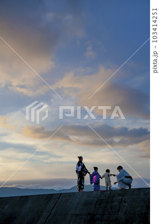 夕暮れの防波堤で遊ぶ浴衣姿の4人家族 103414251