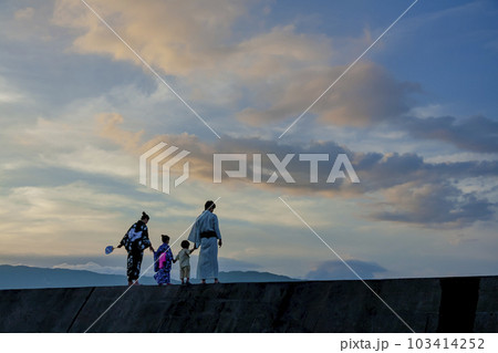 夕暮れの防波堤で遊ぶ浴衣姿の4人家族 103414252