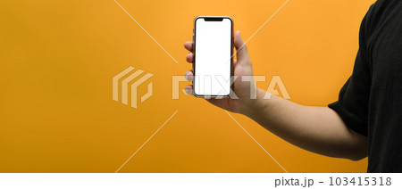 Hand holding mockup smartphone over yellow background. Empty screen for your webpage or advertise text Hand holding mockup smartphone over yellow background. Empty screen for your webpage or advertise text 103415318