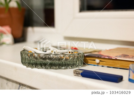 Glass ashtray with cigarette butts in sunlight Glass ashtray with cigarette butts in sunlight 103416029