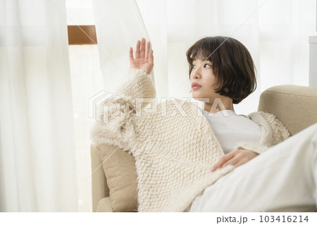 カーテンの隙間から外を見る若い女性 カーテンの隙間から外を見る若い女性 103416214