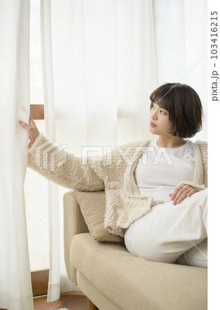 カーテンの隙間から外を見る若い女性 カーテンの隙間から外を見る若い女性 103416215