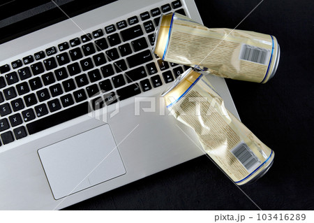 Empty crushed cans of beer on a laptop keyboard on a black background. Drunken fights on social media Empty crushed cans of beer on a laptop keyboard on a black background. Drunken fights on social media 103416289