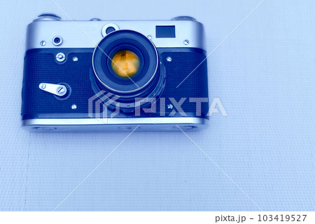 Old vintage film photo camera with lens isolated on pale blue 103419527
