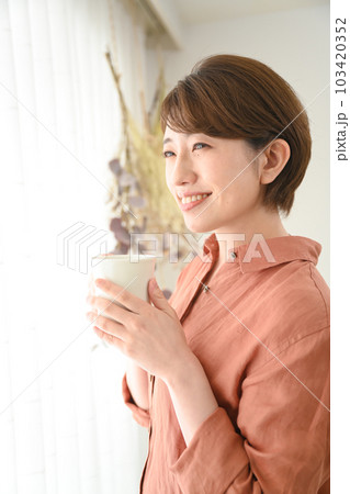 女性ポートレート、部屋でマグカップを持つ女性 女性ポートレート、部屋でマグカップを持つ女性 103420352