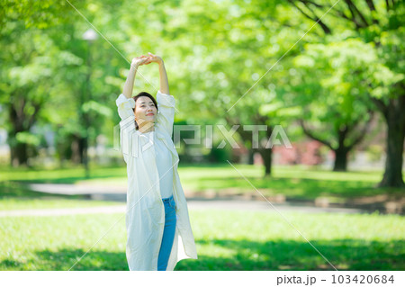 新緑の公園で伸びをする女性  103420684