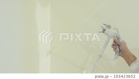 Close up of man painter paints the walls with paint spray gun. Airless spray painting. 103423652