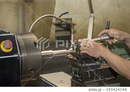 The machine operator working with lathe machine. 103424148