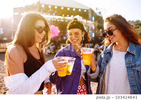 Girlfriends drinking beer and having fun at music festival. Friendship and celebration. Beach party. Girlfriends drinking beer and having fun at music festival. Friendship and celebration. Beach party. 103424641