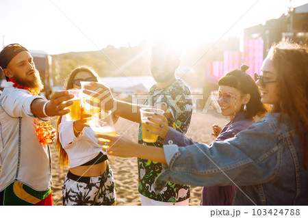 Young happy friends drinking beer and having fun at music festival together. Friendship. 103424788