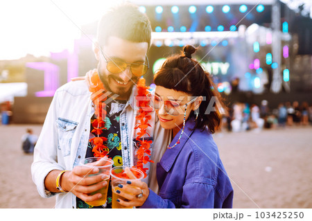 Young and cheerful couple at music festival. Happy friends drinking beer and having fun. Young and cheerful couple at music festival. Happy friends drinking beer and having fun. 103425250