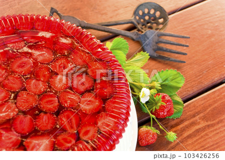 Village life. Summer period. Cake with strawberries and whipped cream decorated with leaves on wooden background 103426256