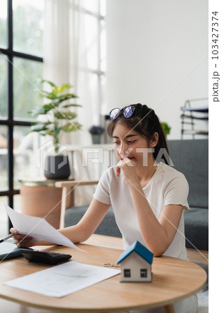 Asian accounting professional calculating household bills, reviewing and analyzing household bills, and filing tax returns 103427374