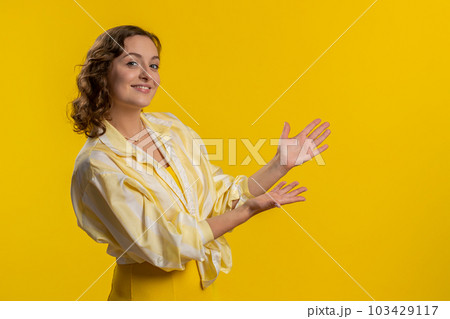Young woman showing thumbs up and pointing at left on blank space, place for your advertisement logo Young woman showing thumbs up and pointing at left on blank space, place for your advertisement logo 103429117