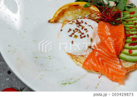 Summer healthy fastfood lunch, breakfast with Pancake with red fish, avocado and egg for breakfast. Aesthetic still life, healthy food concept Summer healthy fastfood lunch, breakfast with Pancake with red fish, avocado and egg for breakfast. Aesthetic still life, healthy food concept 103429873
