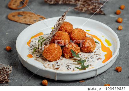 Potato croquettes - mashed potatoes balls breaded and deep fried, served with different sauce. 103429883