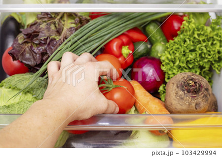 Mans hand is opening drawer of refrigerator with vegetables. Mans hand is opening drawer of refrigerator with vegetables. 103429994