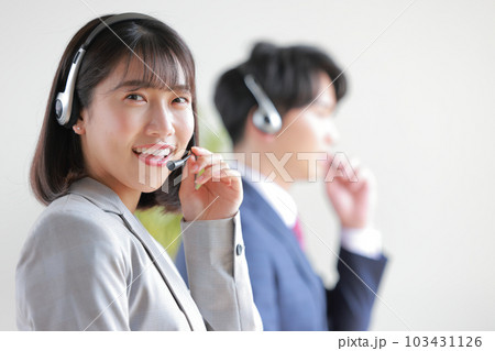 ヘッドセットを支え明るく応対する女性オペレーター2 103431126