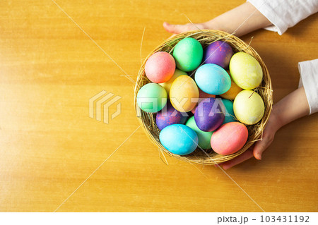 A girl, five years old, holding a basket with many colored Easter eggs in her hands. A girl, five years old, holding a basket with many colored Easter eggs in her hands. 103431192