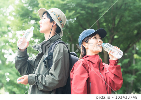 森の中で水分補給をするカップル 103433748